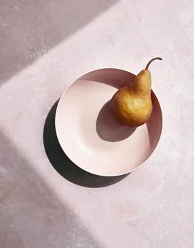 Single Pear in Pink Bowl with Dramatic Shadow Stock Photos