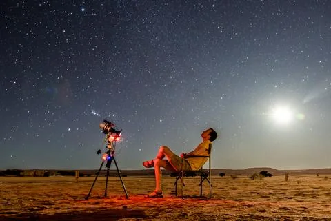 Single person stargazing with telescope under clear sky and full moon Stock Photos