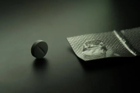 Single pill standing next to empty blister pack Stock Photos