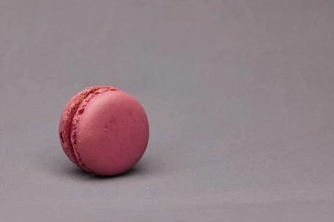 Single pink macaron lying sideways on gray background Foto stock