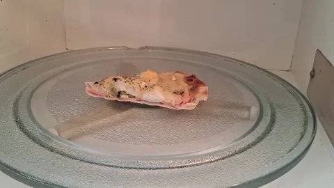 Single pizza slice rotating inside microwave oven for video motion Stock Footage 337896978