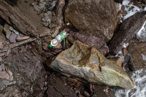 A single plastic bottle is washed up between rocks on the coastline of Irelan Stock Photos