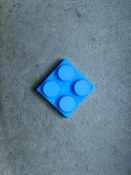 Single plastic building block on a gray textured background Stock Photos