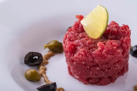 Single portion of beef tartar steak on white plate Stock Photos