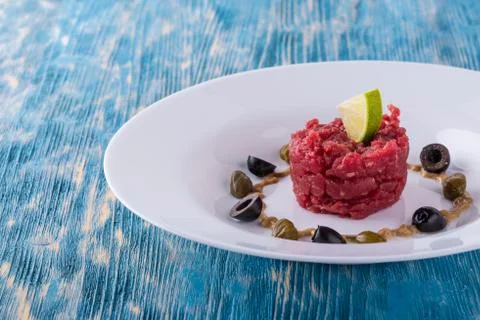 Single portion of tartar steak on white plate Stock Photos