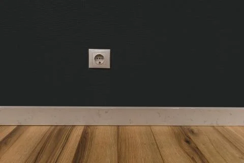 Single power socket in empty wall over wooden floor Stock Photos