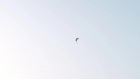 Single powered paraglider flying through vast pastel sky high above distant Stock Footage 331159149