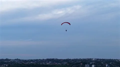Single powered paraglider silhouetted against cloudy sky at Balneario Costa 動画素材 328512917