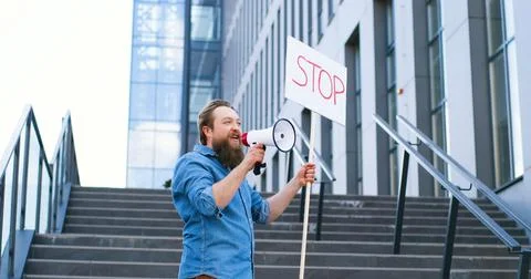 Single protest of Caucasian man with beard talking and screaming in megaphone Stock Photos