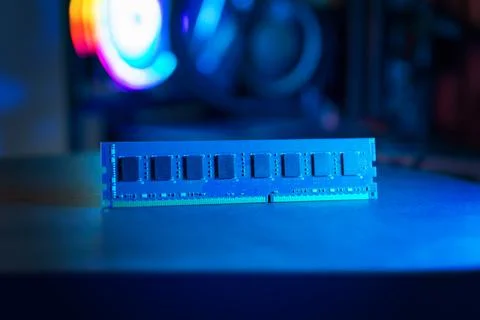 Single RAM memory module on desk with blue lighting, modern gaming computer.. Stock Photos