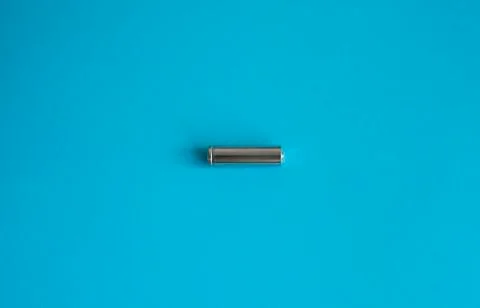 A single rechargeable battery on blue background. Silver alkaline AA battery for Stock Photos