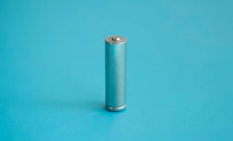 A single rechargeable battery on blue background. Silver alkaline AA battery for Stock Photos