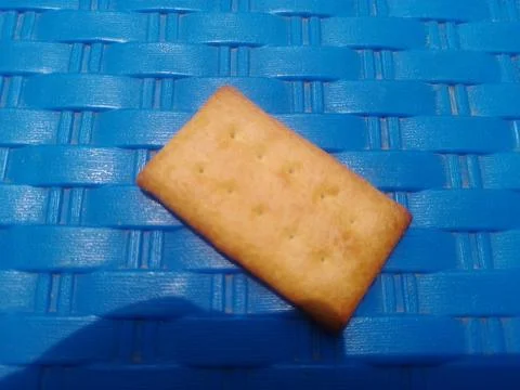 Single rectangular cracker on blue background. 스톡 사진