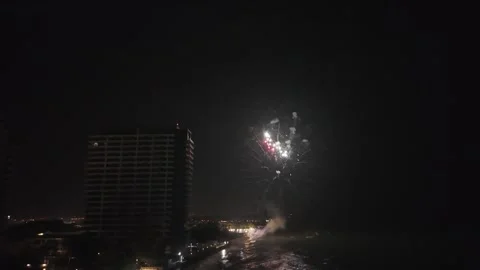 Single Red and White Firework Bursting in the Night Sky Above a Coastal Hotel Video stock 334799903