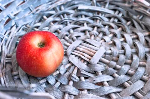 Single Red Apple in a Gray Wicker Basket. Copy Space. Stock Photos