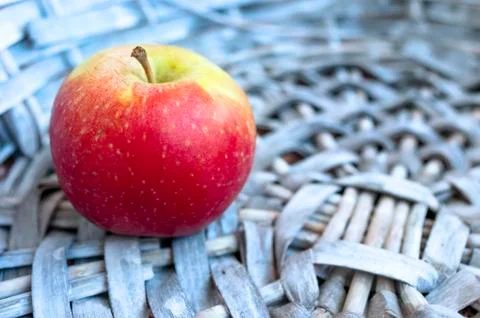 Single Red Apple in a Gray Wicker Basket. Copy Space. Stock Photos