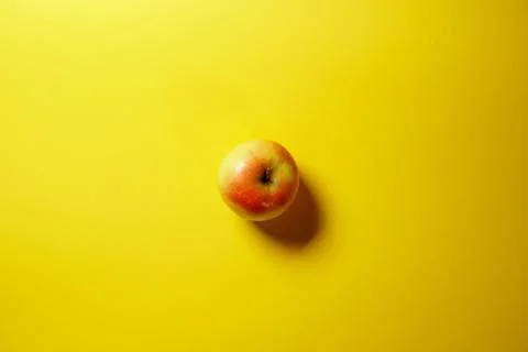 Single red apple isolated on yellow background Stock Photos