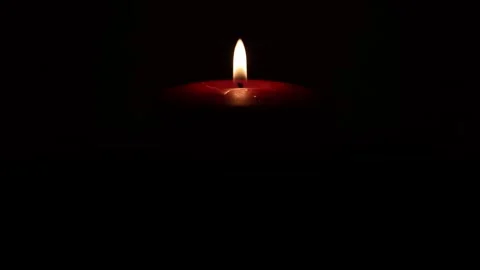 A single red candle casts a gentle glow in the darkness creating a serene a.. Stock Footage 334352163