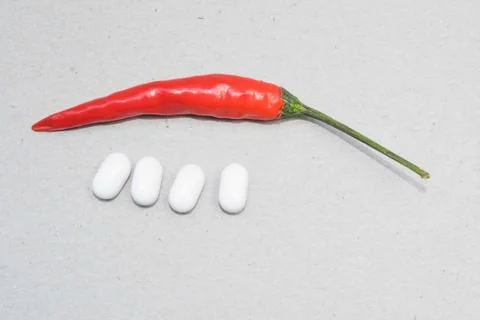 Single red chilli pepper and four white capsules on a white background Stock Photos