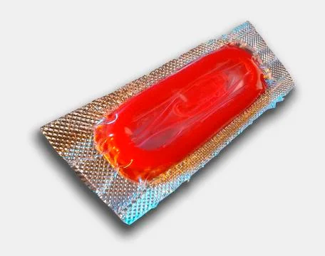 SINGLE RED CONDOM IN FOIL WRAPPER ON WHITE BACKGROUND Stock Photos