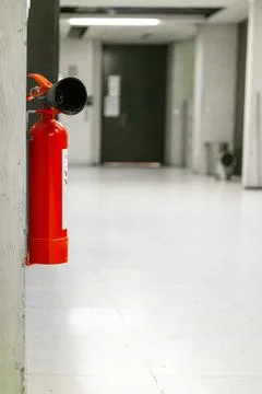Single red fire extinguisher mounted on a wall inside an empty building corri Fotos de archivo