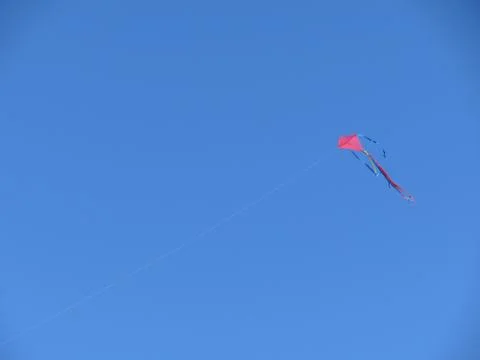 Single red flying kite on a clear blue sky Stock Photos