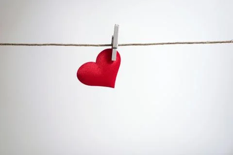 Single red heart hanging from string by clothes peg on white background Stock Photos