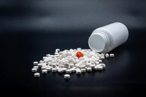 A single red pill in a heap of white pills Stock Photos