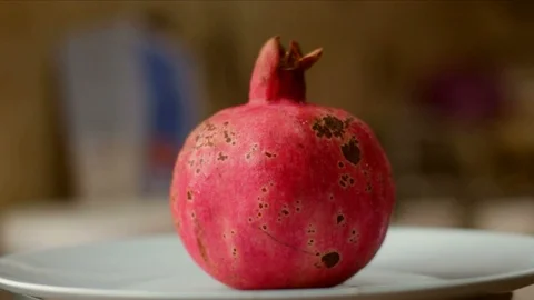 Single red pomegranate on plate rotating. Loop video. Stock Footage 87971599