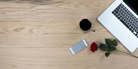 Single red rose with laptop computer, smartphone and coffee on wood desk Stock Photos