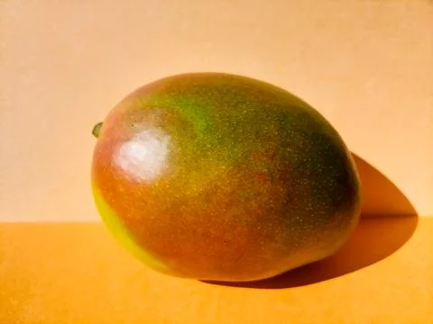 Single Ripe Mango on an Orange Background Stock Photos