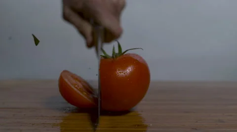 A single ripe tomato on a cutting board, a knife cuts it in slow motion, 2 Stock Footage 64341173