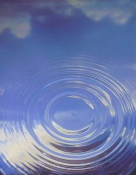 A single rippple in water with a reflection of the clouds and sky Stock Photos