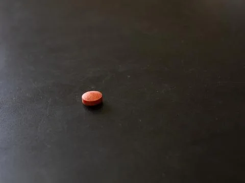 Single round tablet on dark tabletop surface Stock Photos