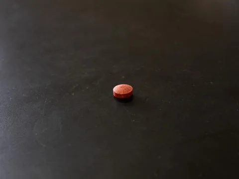 Single round tablet on dark tabletop surface Stock Photos