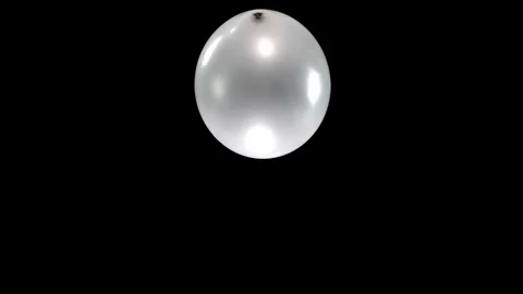 Single Silver Balloon Spinning and Falling Down Against a Black Background with Stock Footage 305012903