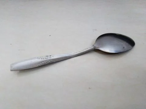 Single silver spoon rests on a light colored surface Stock Photos