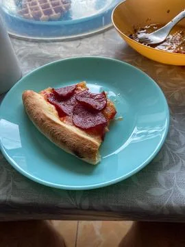 Single Slice of Pepperoni Pizza on a Light Blue Plate Stock Photos