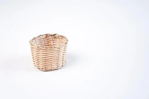 A single small empty woven wicker basket placed on the left side of a plain.. Stock Photos