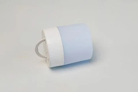 A single small portable electric lantern light lying horizontally on a plai.. Stock Photos