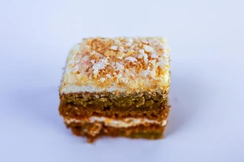 Single small square of nut and sponge layered cake sprinkled with glistening Stock Photos