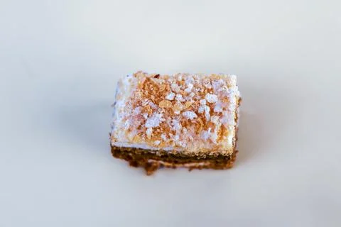 Single small square of nut and sponge layered cake sprinkled with glistening Stock Photos