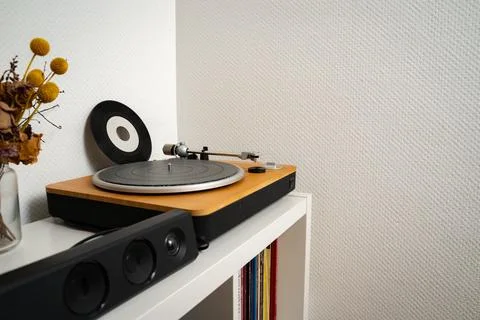 Single small vinyl disk leaning against wall next to vinyl player Stock Photos