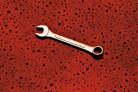 A single spanner on a textured red background Stock Photos