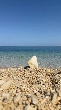 Single Standing Pebble on Pebble Beach Overlooking Turquoise Sea Fotos Stock