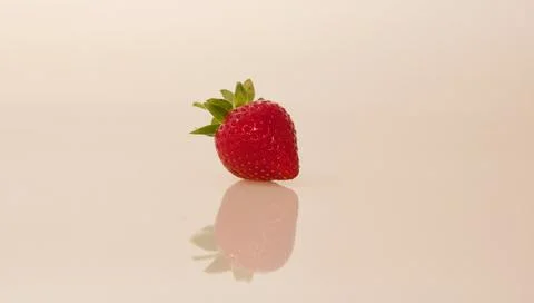 Single strawberry reflected in neutral background with space for copy Stock Photos