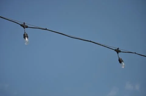 Single string of patio lights, two bulbs against blue sky Foto stock