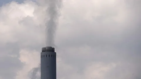 Single tall industrial smoke stack chimney pours smoke into cloudy sky Video stock 223979180