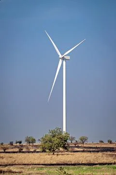 Single, tall Windmills d in an open field with nice, clear blue sky backgroun Stock Photos