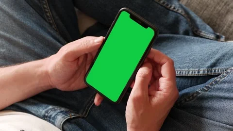 Single Tapping and Holding a Green Screen Smartphone on the Couch at Home Stock Footage 240470702